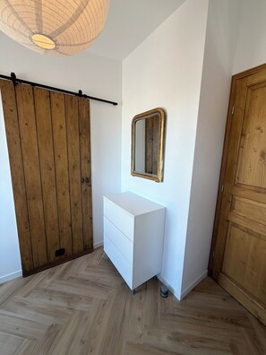 A room with a wooden wardrobe, a white dresser, a mirror, and a wooden door. - Stunning new apartment with 2 terraces and parking (Avignon)