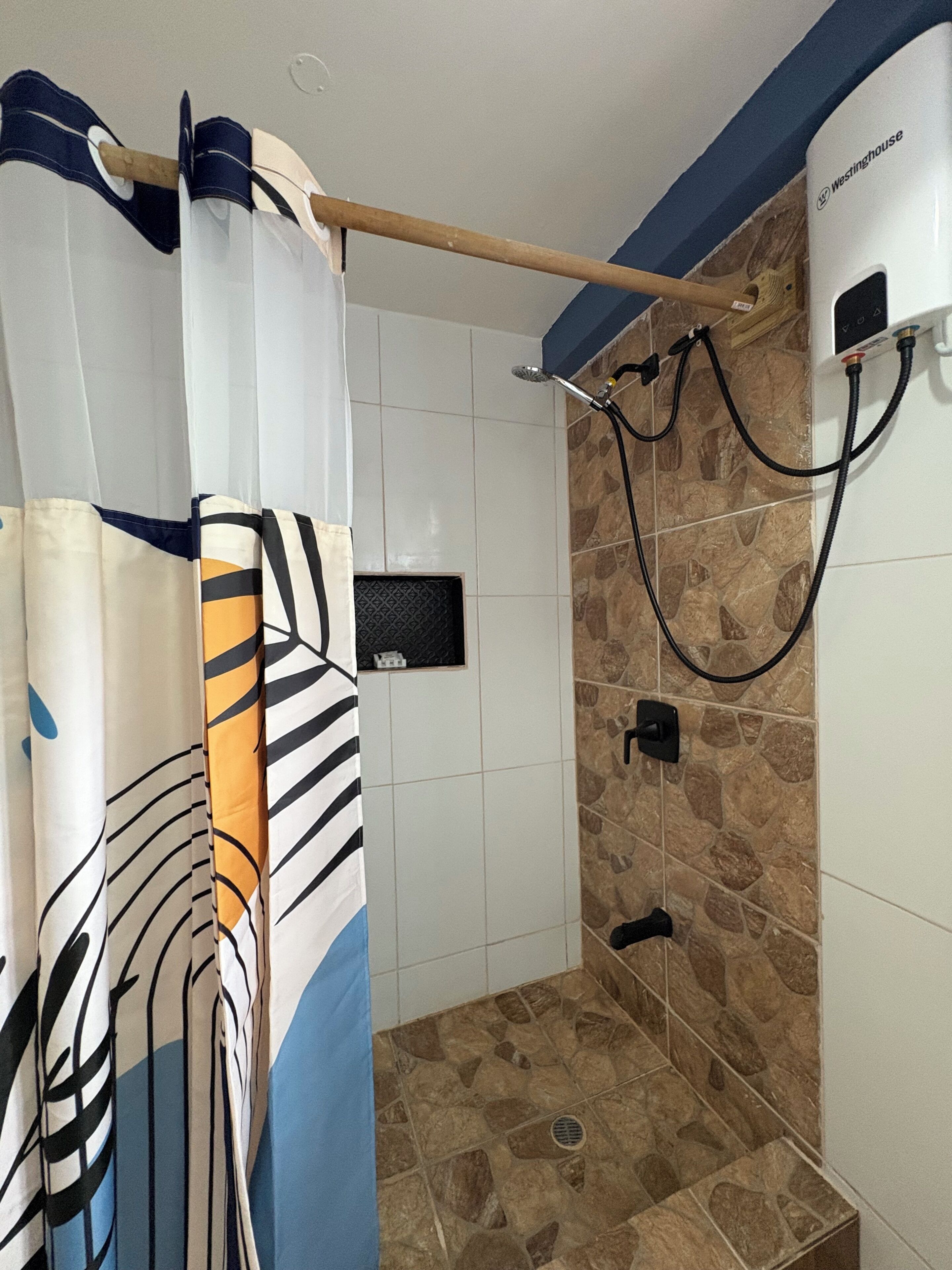 A shower with a curtain, a handheld showerhead, and a wall-mounted control panel.