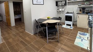 A modern kitchen with a dining area, featuring a built-in oven, a stove, and a wall-mounted shelf with dishes.