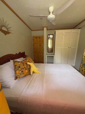 Un dormitorio con cama, armario de madera, espejo y ventilador de techo.