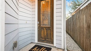 Ein Haus mit einer Holztür, einem Briefkasten und einer Fußmatte mit dem Aufdruck 'hello'.