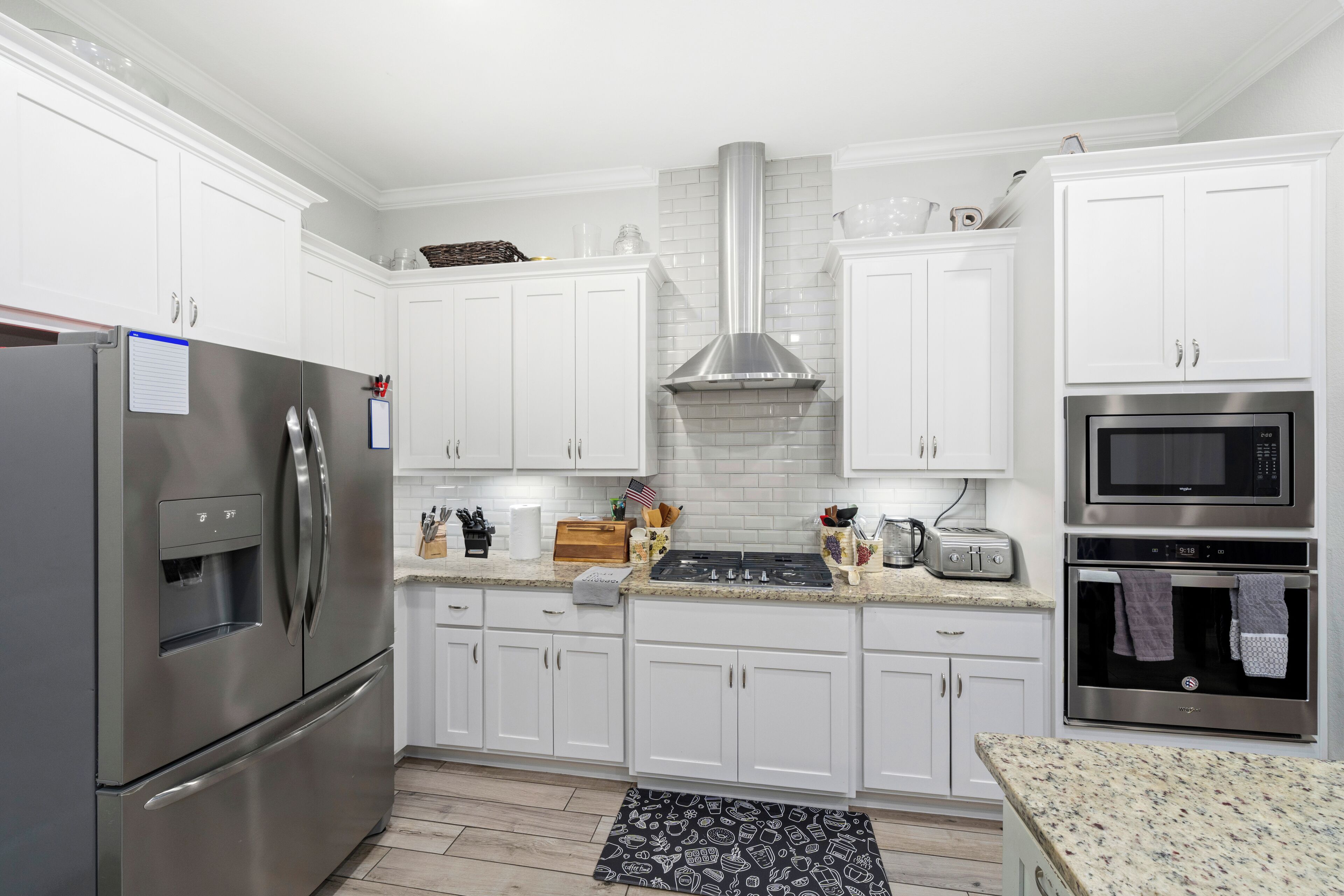 Una cocina moderna con armarios blancos, electrodomésticos de acero inoxidable y un salpicadero de azulejos.