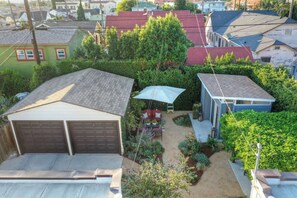 Ein Wohngebiet mit Garage, kleiner Gartenhütte und Garten mit verschiedenen Pflanzen und einer Terrasse.