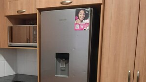 A stainless steel Samsung refrigerator with a water dispenser, located in a kitchen with wooden cabinets and a black countertop. - Lovely 3 Bedroom With Full sea View, Restaurants, (East London)