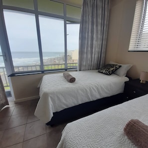 A hotel room with two beds, a view of the sea, and a balcony. - Lovely 3 Bedroom With Full sea View, Restaurants, (East London)