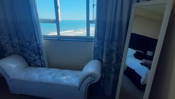 Una habitación con vista al mar, un sofá blanco y un espejo.