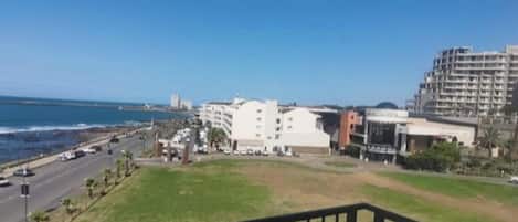 A balcony with a view of a coastal road, buildings, and the ocean.