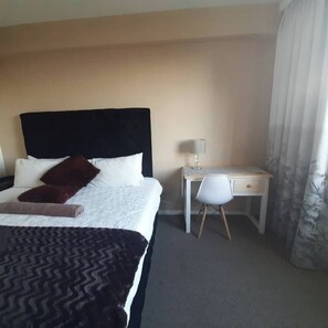 Une chambre d’hôtel avec un lit, un bureau et une chaise.
