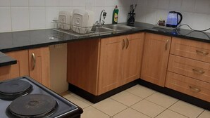 A kitchen with a stove, sink, and wooden cabinets. - Lovely 3 Bedroom With Full sea View, Restaurants, (East London)