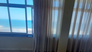 A room with a large window, a yellow tufted ottoman, and a view of the ocean. - Lovely 3 Bedroom With Full sea View, Restaurants, (East London)