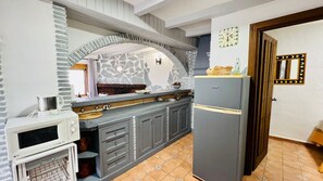 Eine Küche mit Steinrückwand, grauen Schränken, einer Mikrowelle und einem Kühlschrank.