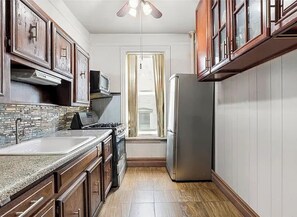 A kitchen with a stove, sink, and refrigerator. - Quiet Old Brooklyn Charm Upstairs 2-bedroom/1-bath Unit in E. Flatbush Townhome (Brooklyn)