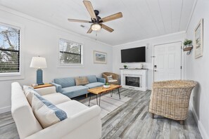 A living room with a sofa, a coffee table, a television, a fireplace, and a ceiling fan. - Updated Condo with pool within walking distance to beach (North Myrtle Beach)