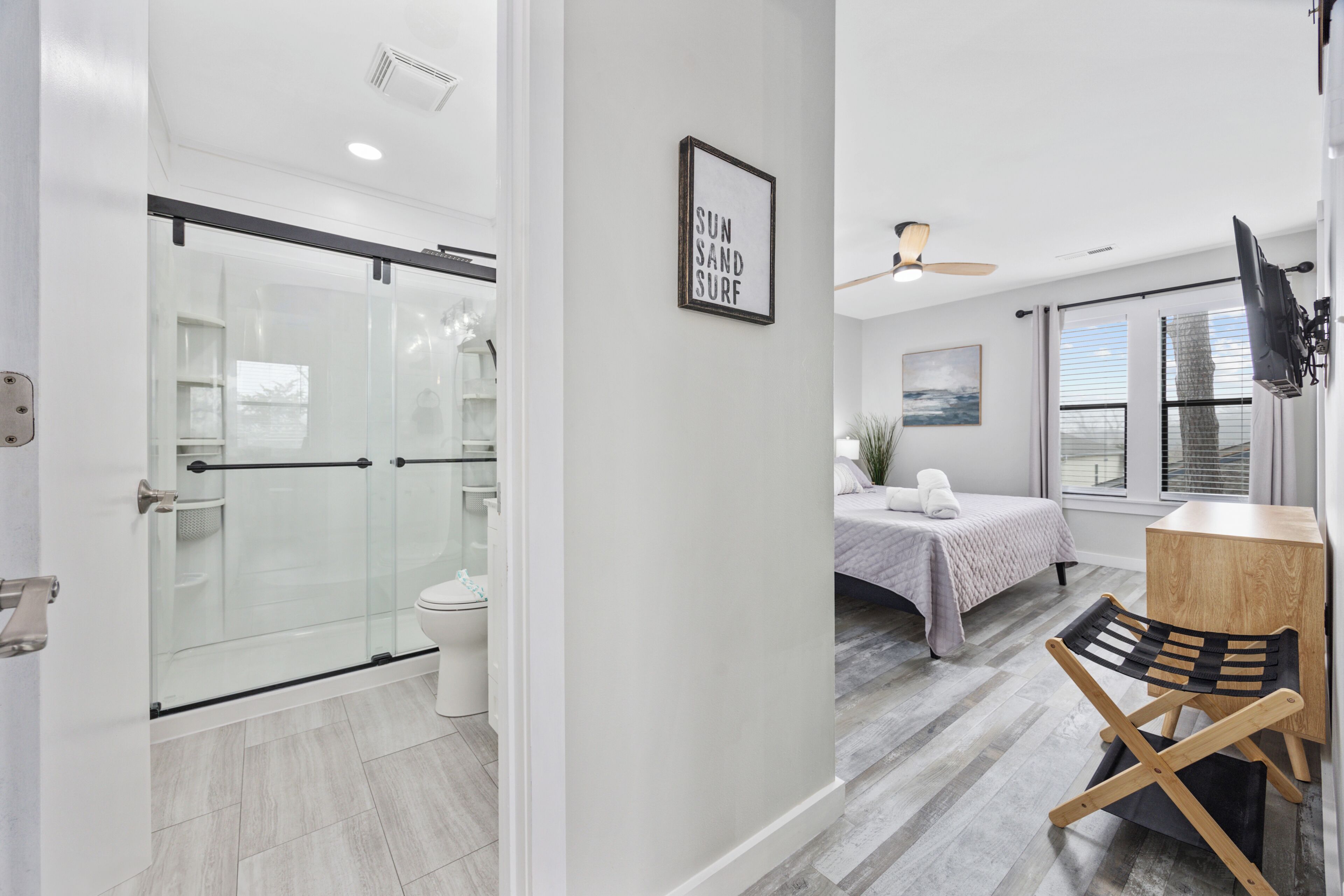 A modern bathroom with a glass shower enclosure, a toilet, and a wooden floor.