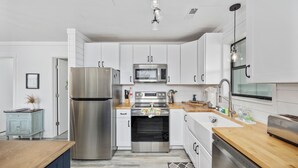A modern kitchen with stainless steel appliances, white cabinetry, and a wooden countertop. - Updated Condo with pool within walking distance to beach (North Myrtle Beach)