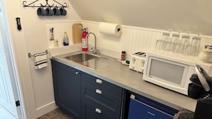 Une cuisine équipée d’un évier, d’une cuisinière, d’un four à micro-ondes et d’un ensemble de couteaux.