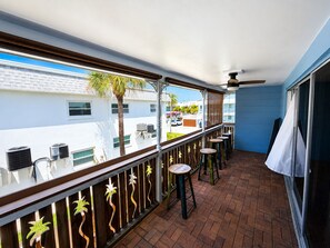 Ein Balkon mit Backsteinboden, einer Brüstung mit Zierelementen und drei Hockstühlen.