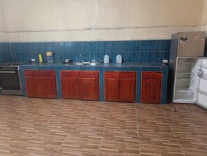 A kitchen with a blue tiled backsplash, wooden cabinets, and a stainless steel sink. -  5000 Square feet house for rent. (Ticuantepe)