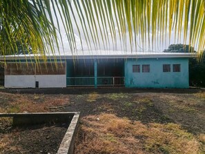 A building with a flat roof, a fenced area in front, and a palm tree in the foreground. -  5000 Square feet house for rent. (Ticuantepe)