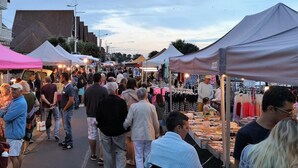 Un marché animé en plein air, avec de nombreux étals et tentes.