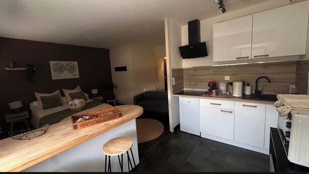 Une cuisine compacte dotée d’un coin bar, de meubles blancs et d’un design moderne.