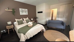 Ein Schlafzimmer mit einem Bett, Nachttischen, einem Sessel, einem Teppich und einem an der Wand befestigten Regal mit einer Pflanze.