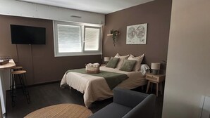 Une chambre à coucher comprenant un lit, une table de chevet, une lampe et un téléviseur fixé au mur.