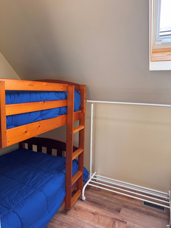 A bunk bed with blue bedding, a white radiator, and wooden flooring.