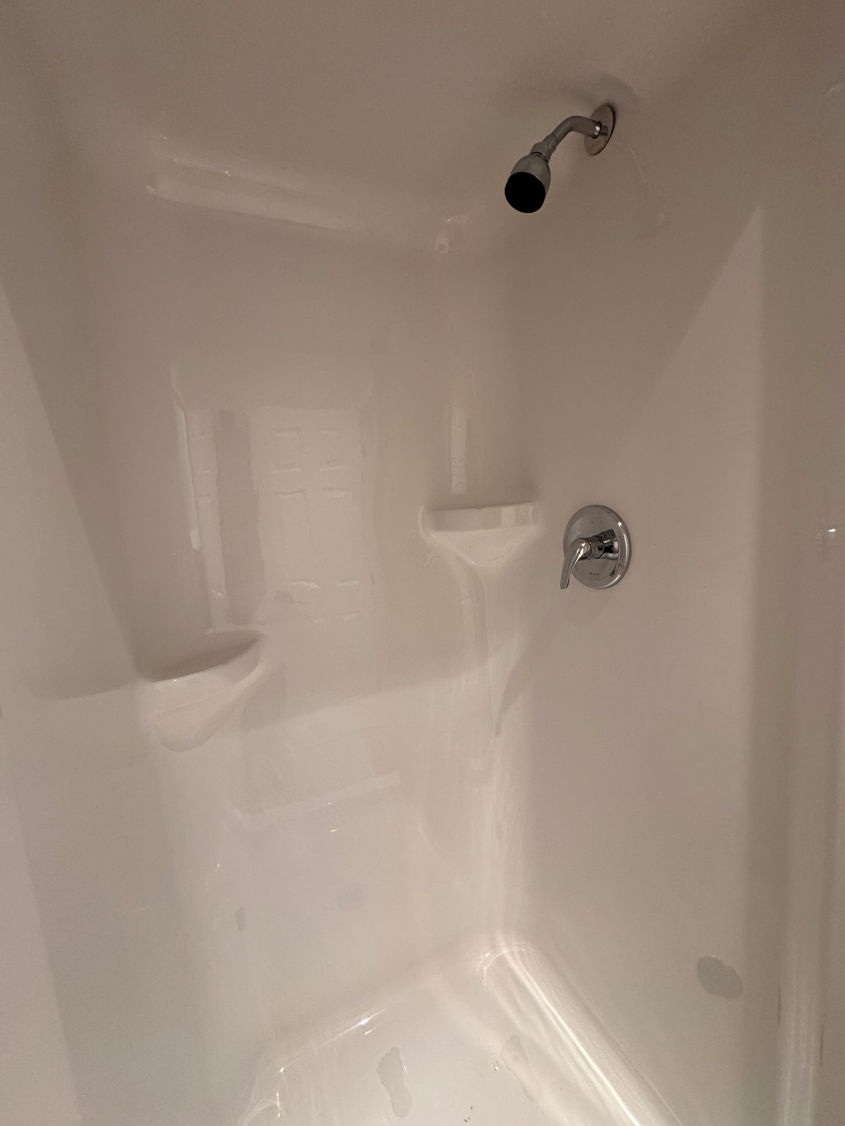 A bathtub with a showerhead, a handheld shower, and a built-in seat.