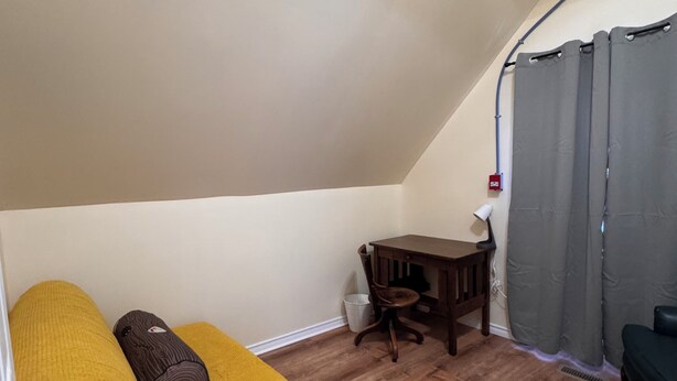 A small, cozy room with a yellow sofa, a wooden table, and a chair.