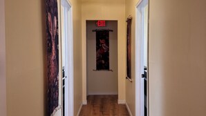 A hallway with wooden flooring, beige walls, and a ceiling light fixture.