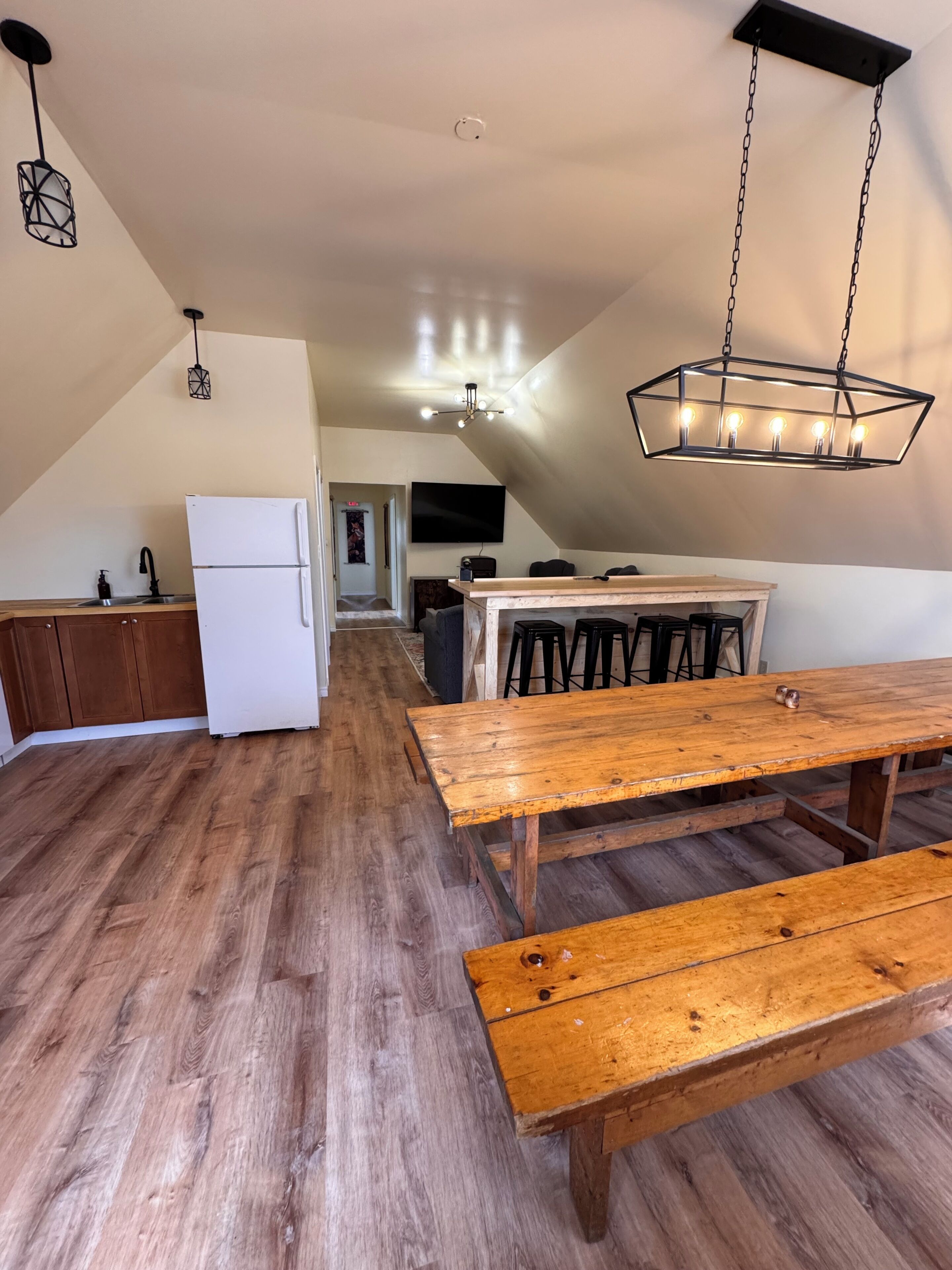 A kitchen with a white refrigerator, wooden cabinets, and a hanging light fixture.