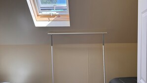 A bedroom with a skylight, a bed, a bench, and a radiator.