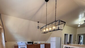 A kitchen with wooden cabinets, a wooden dining table, and a hanging light fixture.