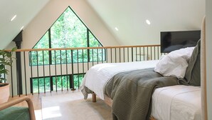 Ein Schlafzimmer mit großem Fenster, einem Bett und einem Fernseher.