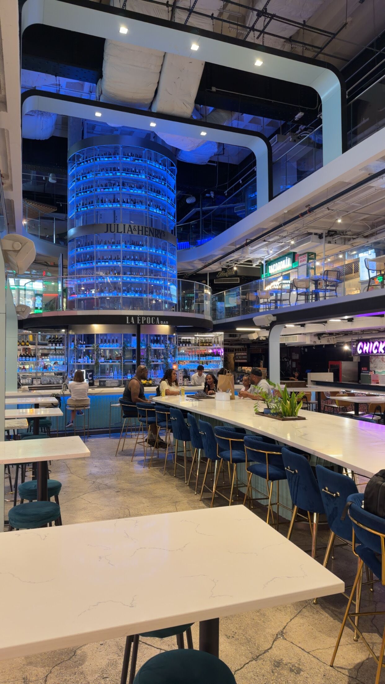Een moderne barzone met een rond, blauw verlicht display, een bargedeelte en zitplaatsen.