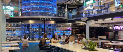 A modern bar area with a circular blue-lit display, a bar counter, and seating.