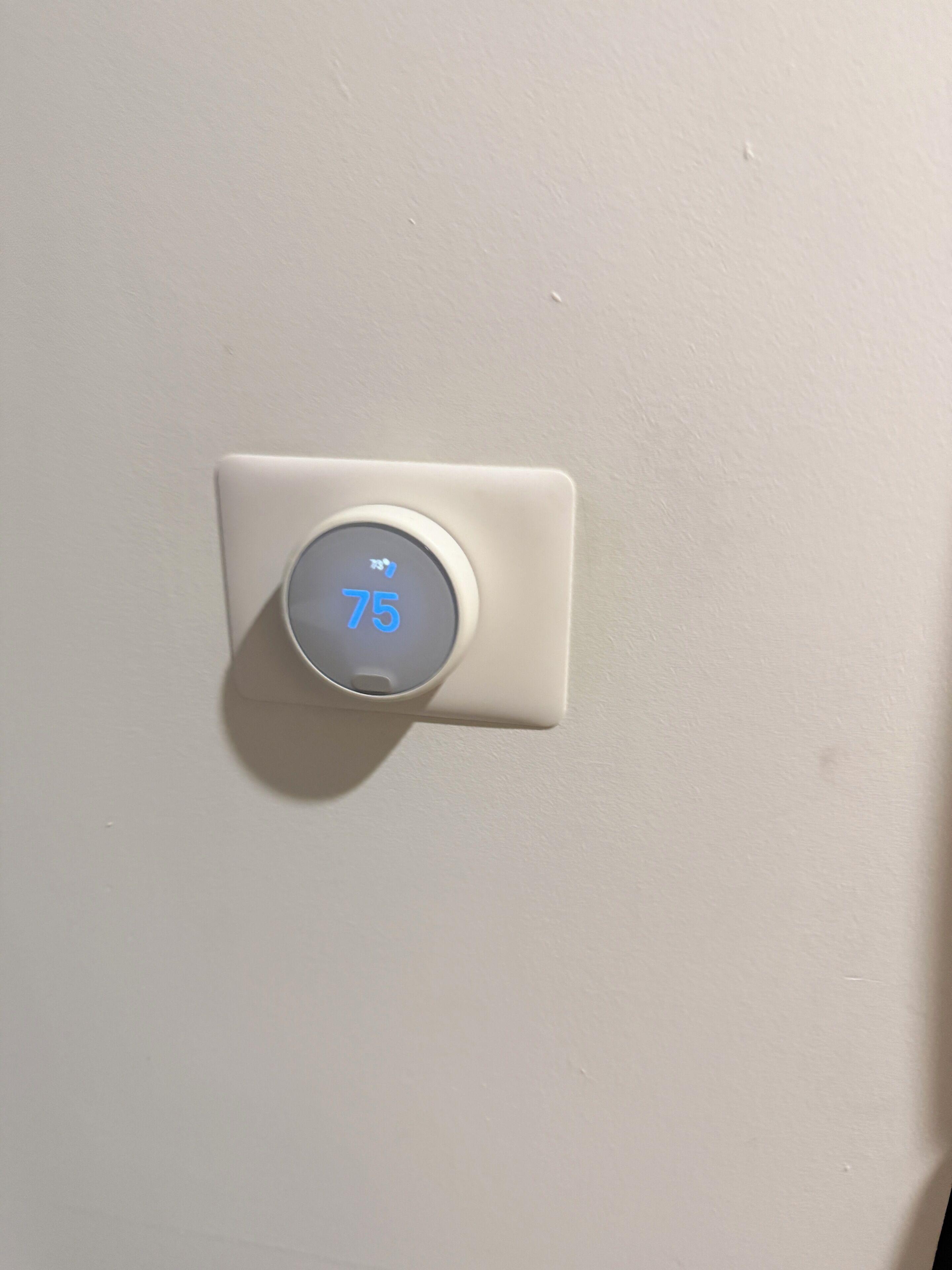 Termostato con pantalla digital que muestra una temperatura de 75 grados.
