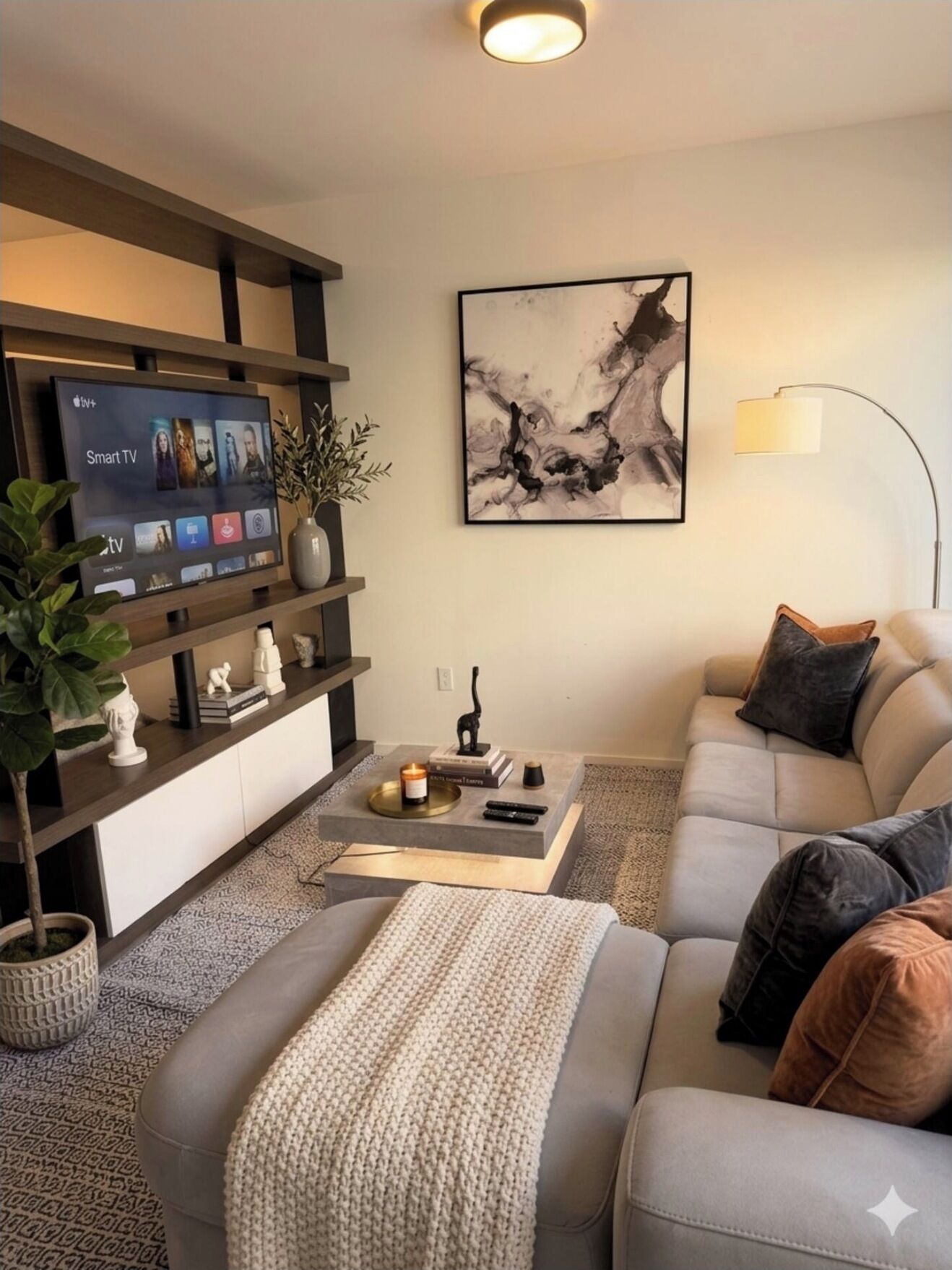 A modern living room with a flat-screen TV, a sofa, a coffee table, and a painting on the wall.