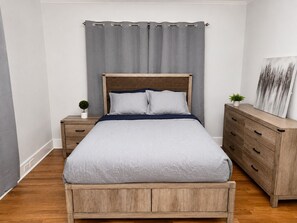 Ein Schlafzimmer mit einem Bett, einem Nachttisch, einer Kommode und einem Wandbild.