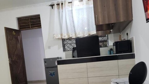 A compact kitchen with a built-in stove, a microwave, and a small refrigerator. - SPACIOUS VIP 1 BEDROOM with ROOFTOP SWIMMING POOL AVAILABLE (Mtwapa)