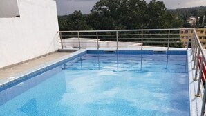 A rooftop swimming pool with a view of the surrounding buildings and trees. - SPACIOUS VIP 1 BEDROOM with ROOFTOP SWIMMING POOL AVAILABLE (Mtwapa)