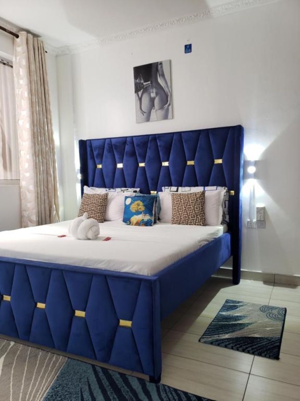 A bed with a blue upholstered headboard, a white mattress, and decorative pillows.