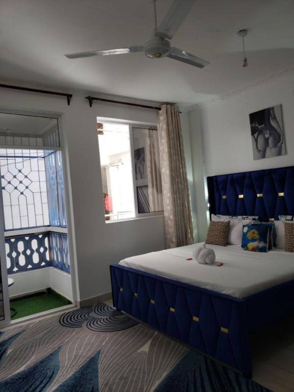 Une chambre à coucher avec un lit, un ventilateur de plafond, une fenêtre avec des rideaux et une vue sur l’extérieur.