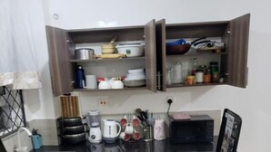 A compact kitchen with a black countertop, wooden cabinets, and a built-in microwave. - SPACIOUS VIP 1 BEDROOM with ROOFTOP SWIMMING POOL AVAILABLE (Mtwapa)