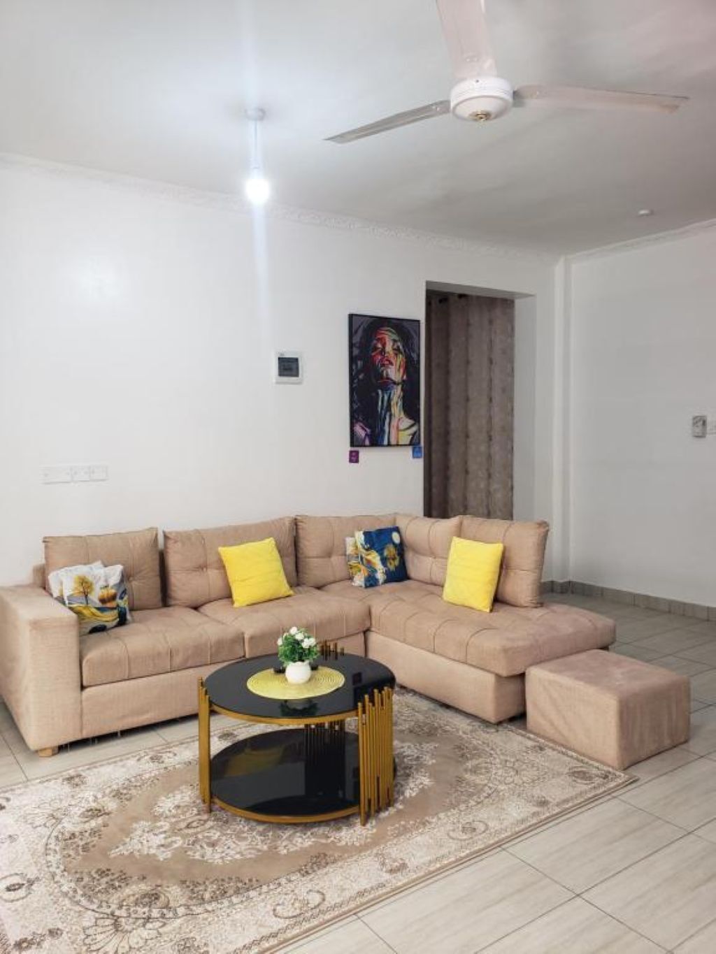 A living room with a beige sectional sofa, a round coffee table, and a patterned rug.