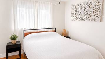 Une chambre à coucher comprenant un lit, une table de chevet, un élément décoratif fixé au mur et un ventilateur de plafond.
