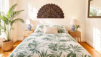 Un dormitorio con una cama, dos mesitas de noche, un adorno en la pared y una planta en maceta.
