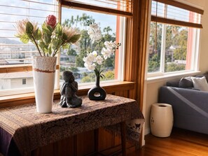 Et værelse med et bord ved et vindue, en sofa og en dekorativ vase med blomster.