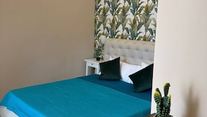 Una camera da letto con un letto, un comodino, una cassettiera e una pianta in vaso.